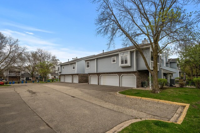 view of front of property with a residential view, a chimney, driveway, brick siding, and central AC unit