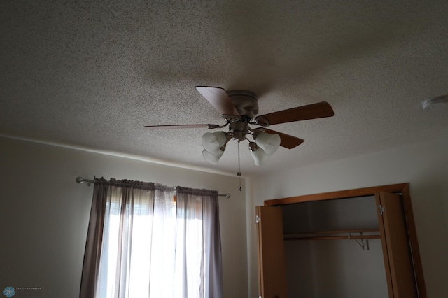 detailed view of a textured ceiling, a ceiling fan, and a smoke detector
