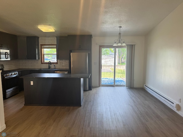 316 4th S, Breckenridge, MN 56520 - kitchen featuring stainless steel appliances, a baseboard heating unit, a textured ceiling, tasteful backsplash, and dark countertops