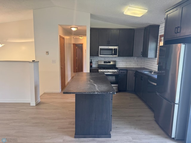 316 4th S, Breckenridge, MN 56520 - kitchen with stainless steel appliances, vaulted ceiling, dark countertops, tasteful backsplash, and light wood finished floors