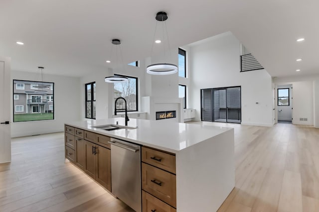 1796 Cobblestone Ct, Hastings, MN 55033 - kitchen featuring stainless steel dishwasher, a sink, a fireplace, open floor plan, and hanging light fixtures