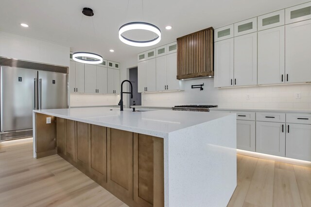 1796 Cobblestone Ct, Hastings, MN 55033 - kitchen featuring stainless steel built in refrigerator, light wood-style flooring, tasteful backsplash, a spacious island, and recessed lighting