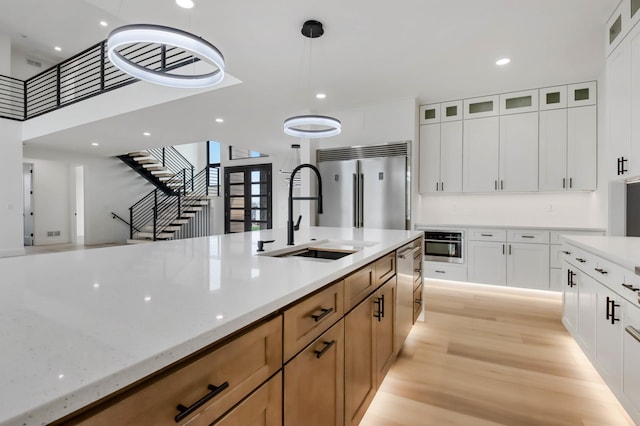 1796 Cobblestone Ct, Hastings, MN 55033 - kitchen featuring a sink, stainless steel appliances, glass insert cabinets, light wood-style flooring, and light stone counters