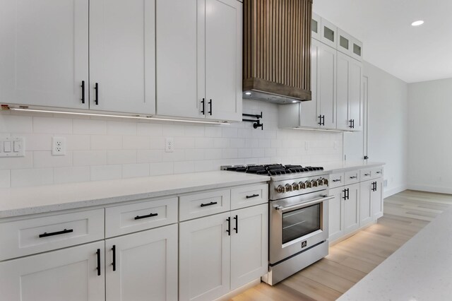 1796 Cobblestone Ct, Hastings, MN 55033 - kitchen featuring high end stainless steel range, custom range hood, white cabinetry, light wood-style floors, and backsplash