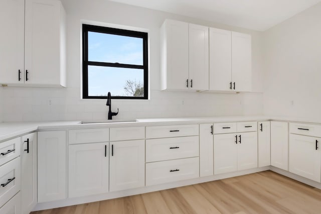 1796 Cobblestone Ct, Hastings, MN 55033 - kitchen featuring a sink, decorative backsplash, white cabinets, and light wood finished floors