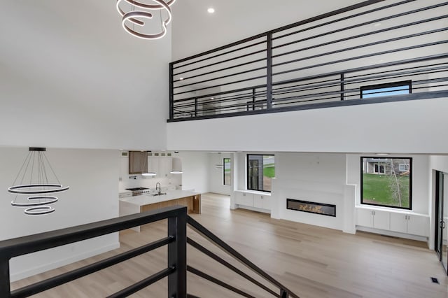 1796 Cobblestone Ct, Hastings, MN 55033 - staircase featuring a chandelier, wood finished floors, a towering ceiling, and a glass covered fireplace