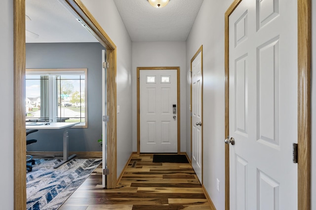 entryway featuring wood finished floors, an office area, baseboards, and a textured ceiling