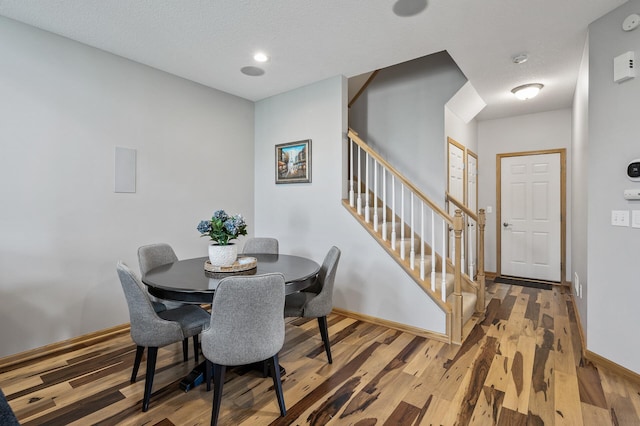 dining space with stairway, wood finished floors, and baseboards