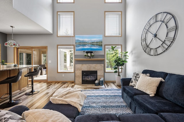 living room with a high ceiling, wood finished floors, a fireplace, and baseboards