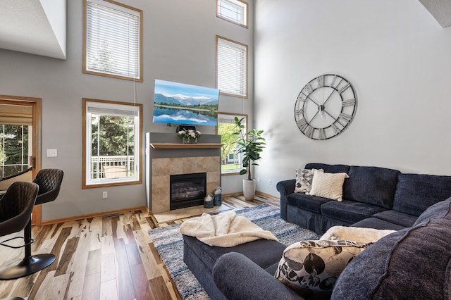 living area featuring a towering ceiling, wood finished floors, plenty of natural light, and baseboards
