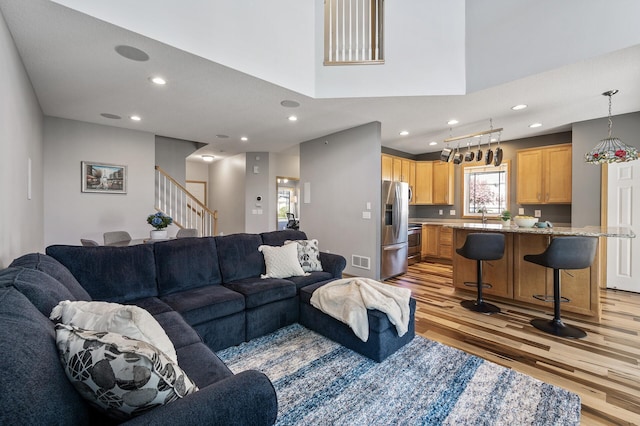 living room featuring light wood-type flooring, recessed lighting, and stairway