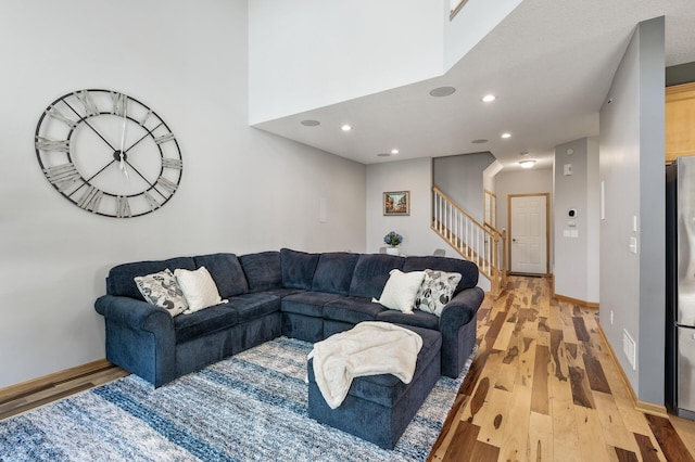 living area featuring light wood-style flooring, stairway, recessed lighting, and baseboards