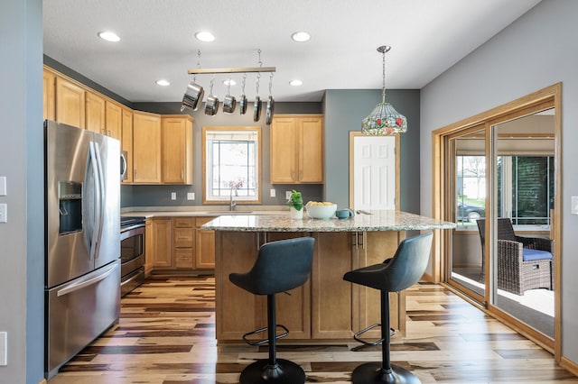 kitchen featuring appliances with stainless steel finishes, light wood-type flooring, light brown cabinetry, a sink, and recessed lighting