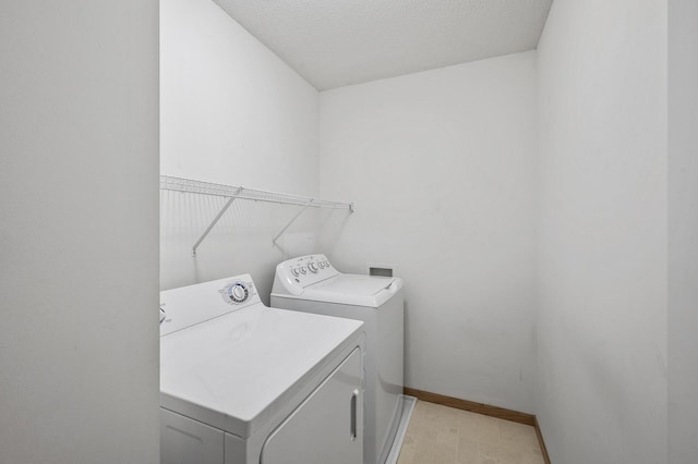 washroom with washer and dryer, baseboards, and a textured ceiling