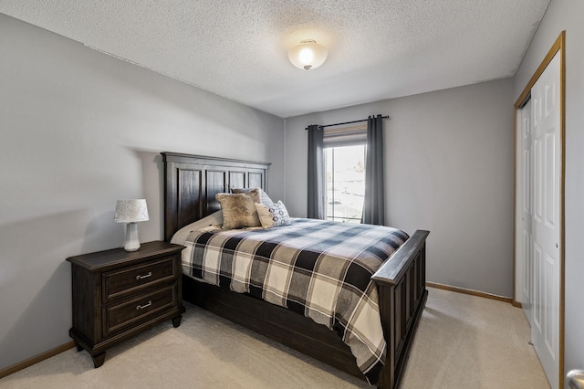 bedroom featuring a closet, light carpet, baseboards, and a textured ceiling