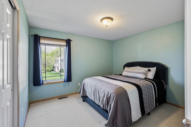 carpeted bedroom with a textured ceiling and baseboards