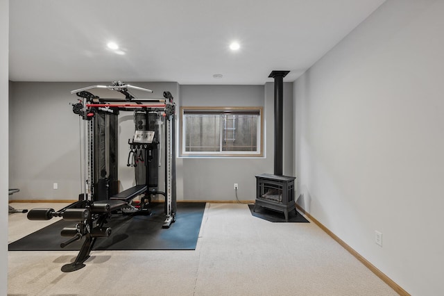 workout room with a wood stove, baseboards, recessed lighting, and carpet flooring