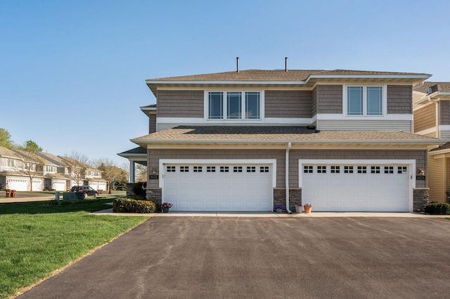 view of front of home featuring a garage, asphalt driveway, stone siding, and a front yard