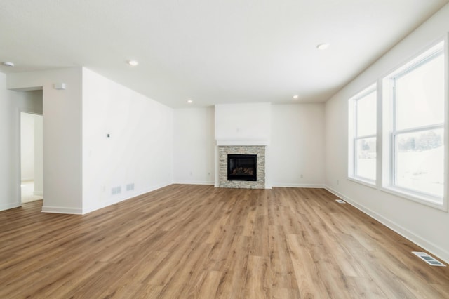 unfurnished living room featuring light wood-style flooring, baseboards, a fireplace, and recessed lighting