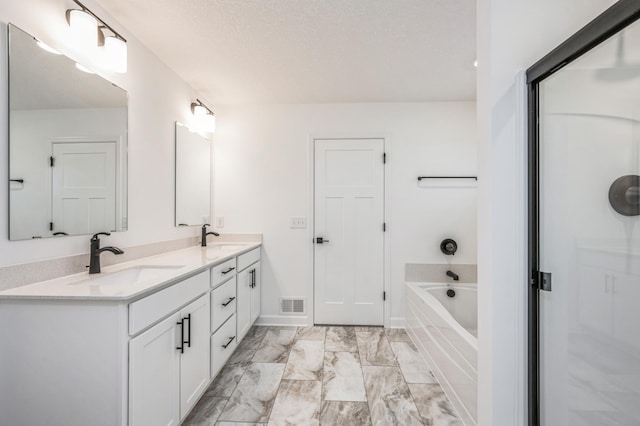 bathroom featuring a garden tub, double vanity, and marble finish flooring