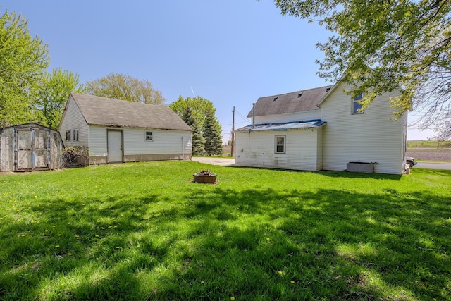 812 Main St, Dodge Center, MN 55927 - rear view of property with a fire pit, a storage shed, a yard, and an outdoor structure