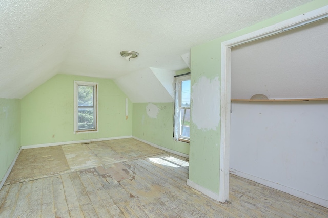 812 Main St, Dodge Center, MN 55927 - additional living space featuring hardwood / wood-style flooring, a textured ceiling, vaulted ceiling, and baseboards