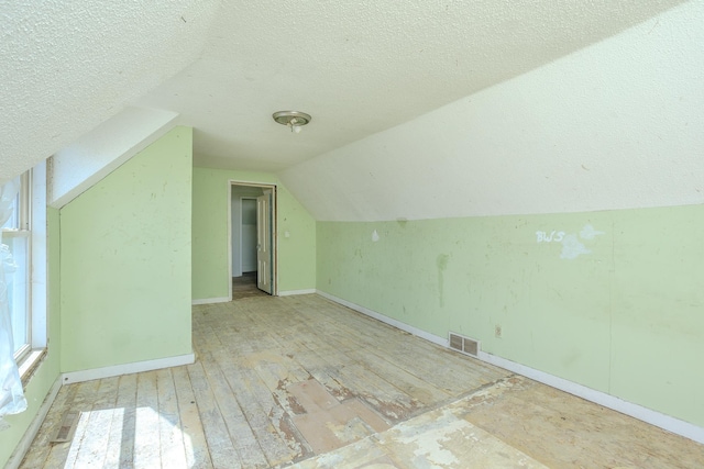 812 Main St, Dodge Center, MN 55927 - additional living space with vaulted ceiling, a textured ceiling, baseboards, and wood finished floors