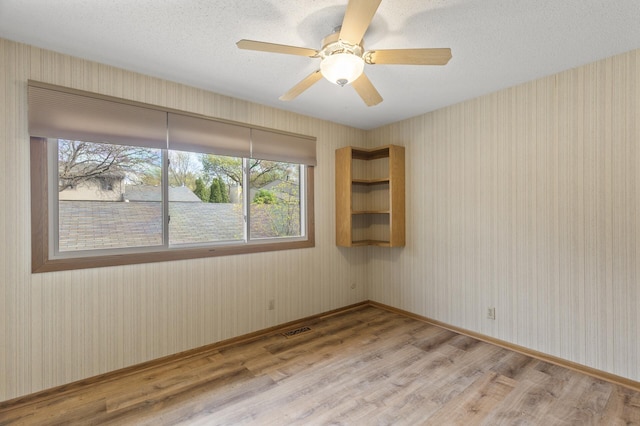 4348 Arden View Ct, Arden Hills, MN 55112 - spare room featuring light wood-type flooring, baseboards, ceiling fan, wallpapered walls, and a textured ceiling
