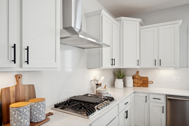 kitchen featuring wall chimney range hood, stainless steel appliances, white cabinetry, and light countertops
