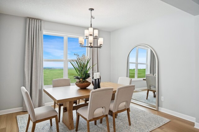 dining area featuring a chandelier, light wood-style floors, and baseboards