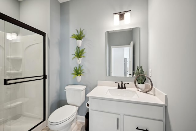 bathroom with a stall shower, vanity, toilet, and baseboards