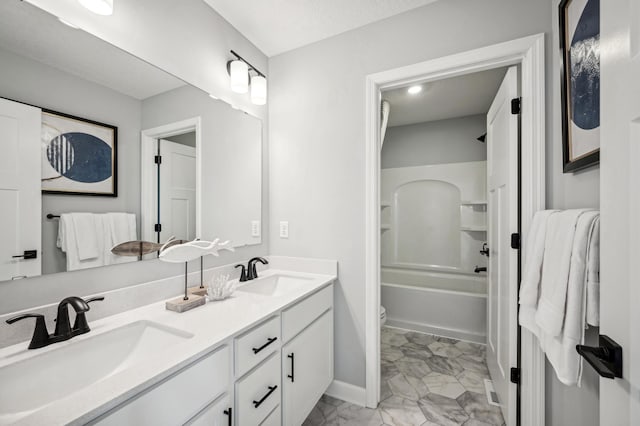 bathroom with double vanity, marble look tile flooring, baseboards, and shower / bath combination