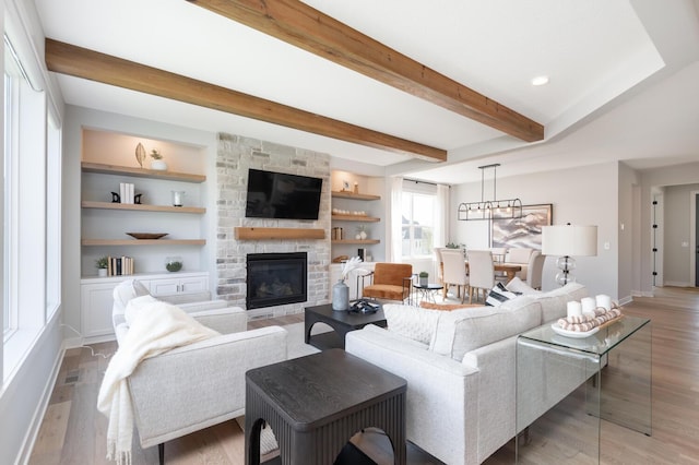 living area with a fireplace, light wood-style floors, beam ceiling, baseboards, and built in features