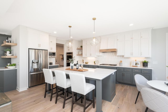 kitchen featuring stainless steel appliances, open shelves, gray cabinetry, backsplash, and light wood-type flooring