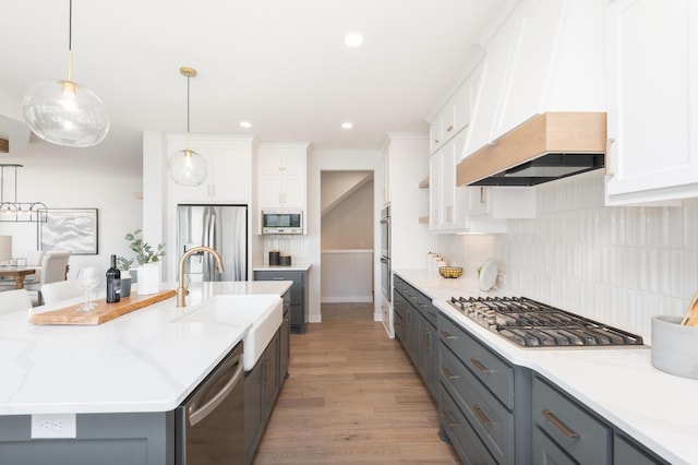 kitchen featuring stainless steel appliances, a sink, light wood-style flooring, white cabinets, and recessed lighting