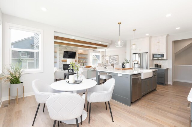 kitchen featuring appliances with stainless steel finishes, gray cabinetry, a sink, light wood-type flooring, and light countertops