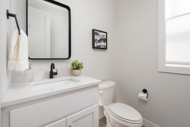 bathroom featuring toilet, vanity, and baseboards