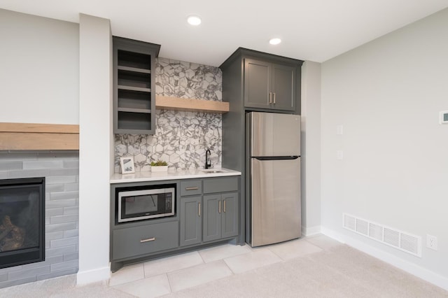kitchen with stainless steel appliances, light countertops, open shelves, decorative backsplash, and a sink