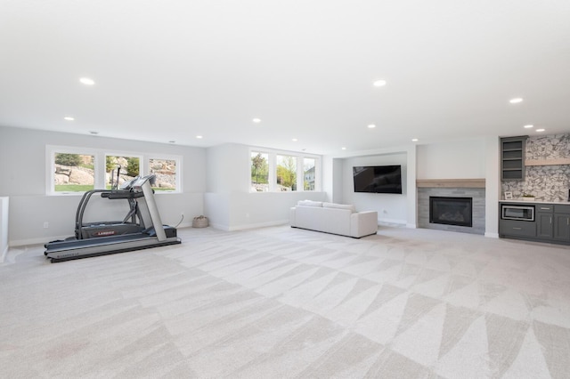 workout area with light carpet, plenty of natural light, recessed lighting, a glass covered fireplace, and baseboards