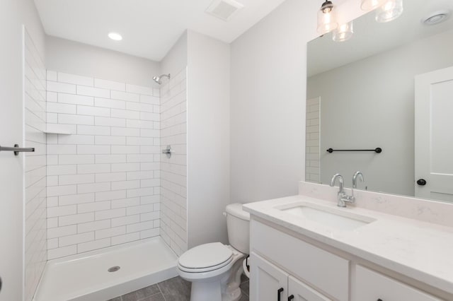 bathroom with toilet, a tile shower, vanity, and recessed lighting
