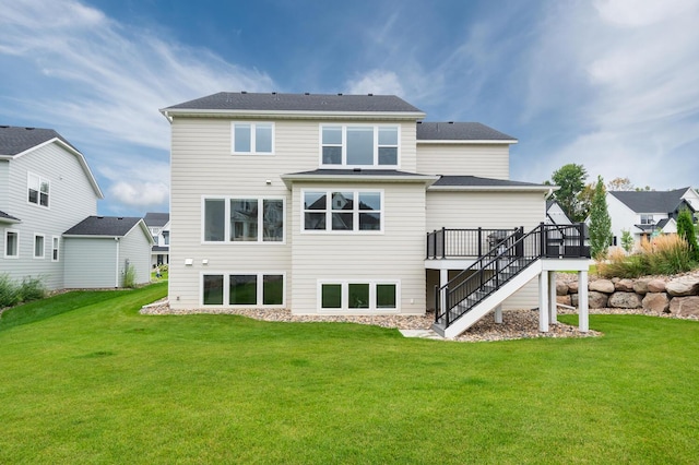 rear view of house featuring stairs, a deck, and a lawn