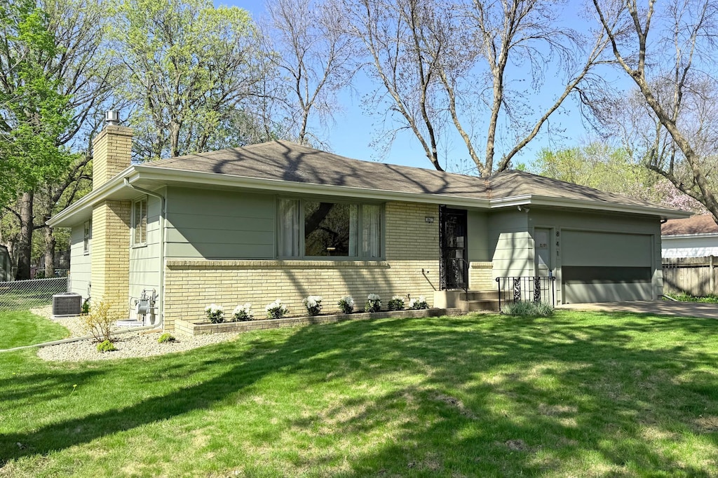 ranch-style home featuring a chimney, brick siding, a garage, and cooling unit