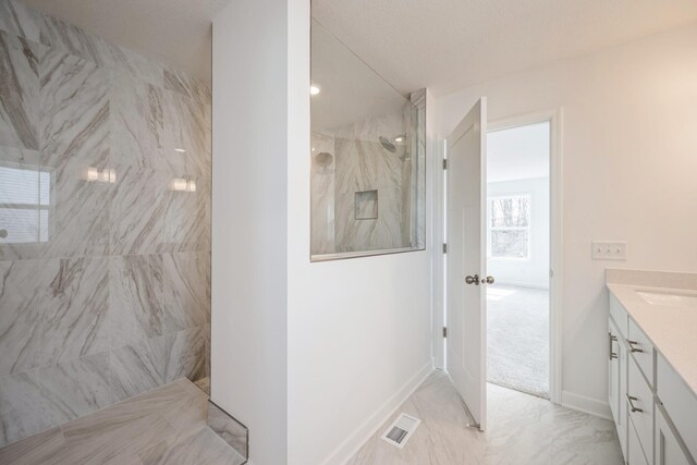 full bathroom with a marble finish shower, vanity, marble look tile flooring, and baseboards