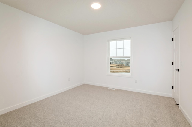 unfurnished room with light carpet and baseboards