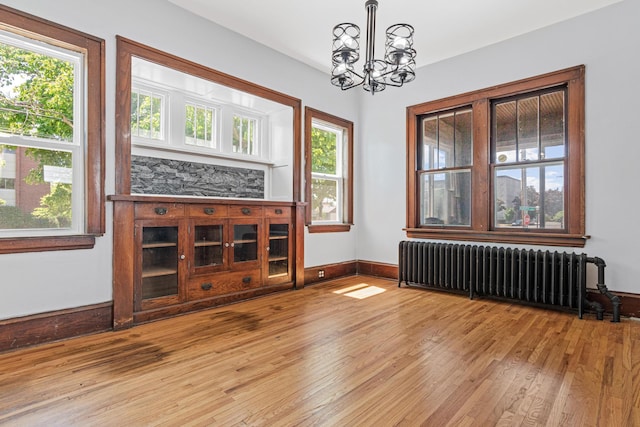 604 Asbury St, Saint Paul, MN 55104 - unfurnished living room with radiator heating unit, wood finished floors, a chandelier, and plenty of natural light