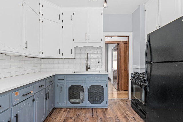 604 Asbury St, Saint Paul, MN 55104 - kitchen with black appliances, a sink, backsplash, wood finished floors, and light countertops