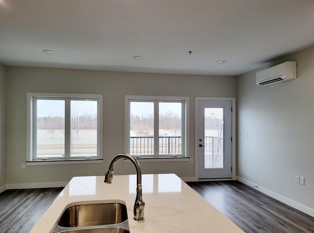 715 Lake Shore Dr NE Unit 105, Bemidji, MN 56601 - kitchen with a wall unit AC, dark wood-style flooring, light stone counters, baseboards, and a sink