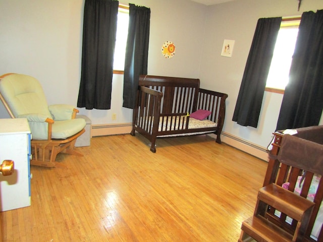 318 3rd St, Dawson, MN 56232 - bedroom featuring baseboard heating, a baseboard heating unit, a nursery area, and wood finished floors