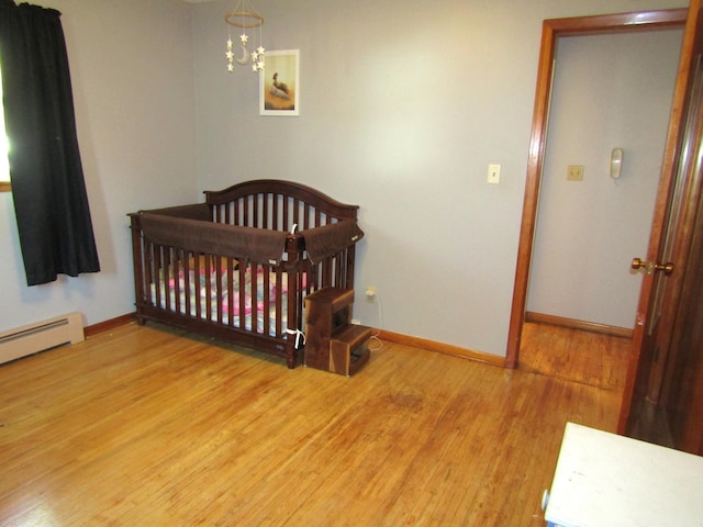 318 3rd St, Dawson, MN 56232 - bedroom with wood finished floors, baseboards, a chandelier, and a nursery area