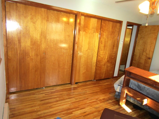 318 3rd St, Dawson, MN 56232 - bedroom with wood finished floors, a ceiling fan, a baseboard radiator, and two closets